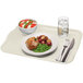 A Cambro rectangular fiberglass tray with food, a glass of water, and a fork and knife on a napkin.