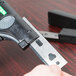 A hand holds a Unger ErgoTec Ninja stainless steel glass scraper blade.
