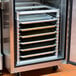 A Channel stainless steel sheet pan rack with trays of food inside a metal cabinet.