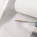 A person using scissors to cut a roll of ARY VacMaster full mesh vacuum packaging bags.