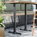 A FLAT Tech bar height table base with two chairs and a plant on it.