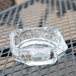 An Anchor Hocking clear glass ashtray on a table.