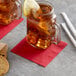 A glass mug with a red Choice cocktail napkin filled with ice and a lemon slice.