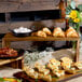 A Tablecraft acacia wood display riser set on a table with food.