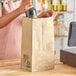 A woman pouring wine into a Duro brown paper bag.