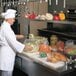 A chef in a commercial kitchen using an LK Packaging plastic bag to store food.