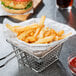 A table with a basket of fries and a newspaper print wrapped burger.