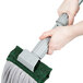 A person holding a Unger SmartColor string mop with a green handle.