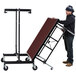 A man pushing a National Public Seating Transfix portable stage with red carpet.