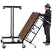 A man pushing a National Public Seating Transfix portable stage table.