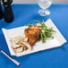 A white platter with food and silver utensils.