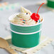 A green 12 oz. paper cup filled with frozen yogurt, topped with sprinkles and a cherry.