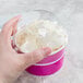 A person holding a Choice pink paper frozen yogurt cup filled with ice cream.