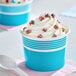 A blue paper cup filled with swirled frozen yogurt and colorful sprinkles.