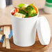 A white paper double-wall food cup with a paper lid, filled with mixed vegetables.
