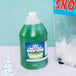 A bottle of Carnival King Lime Snow Cone Syrup with green liquid inside next to a snow cone.