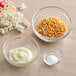 A bowl of corn kernels and a bowl of white powder on a counter.