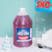 A bottle of Carnival King Strawberry Snow Cone Syrup next to a snow cone.