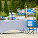 A white table with a Carnival King Lemon Lime Snow Cone Syrup machine and bottles of liquid on it.