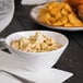 An Urban Mill melamine bowl filled with food on a table next to a plate of chips.