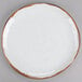 A white GET Rustic Mill irregular round coupe plate with a brown speckled rim.