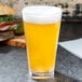 A GET Cubed plastic beverage glass filled with beer on a table.