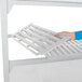 A person assembling a Cambro Camshelving® Premium starter unit with white vented and solid shelves.