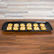 A tray of pastries on a black Sabert catering tray on a table.