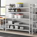 A white Cambro Camshelving unit with vented shelves holding containers.