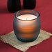 A Sterno Blue Flameless Wax Filled Glass Lamp on a table in a glass holder.