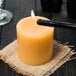 A Sterno beeswax pillar candle with a flame on it.
