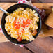 A bowl of elbow macaroni pasta with tomatoes and bacon.