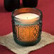 A Sterno teal flameless wax filled glass lamp on a table in a restaurant.