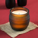 A Sterno green wax filled glass candle lamp on a table in a restaurant.