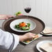 A person holding a Cambro Tavern Tan non-skid serving tray with a plate of salad.