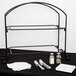 An American Metalcraft black metal two-tier display stand with silverware and napkins on a black table.