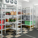 A Cambro Camshelving® Premium stationary add-on unit with vented and solid shelves in a school kitchen.