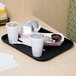 A black customizable plastic fast food tray with food and a white cup with a lid on a table.