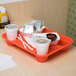 An orange GET Fast Food Tray with food and drinks on it.