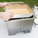 A person preparing food in a Sterno Silver Vein fold away chafer.