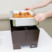 A person using a Sterno Copper Vein chafer to hold food on a table outdoors.