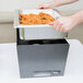 A person using a Sterno full size silver vein chafer to prepare food on a table.