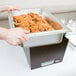 A person holding a tray of food in a Sterno Copper Vein chafing dish with clear dome cover.