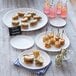 A group of American Metalcraft round melamine plates with sandwiches and drinks on a table.