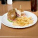 An American Metalcraft white round melamine plate with a sandwich on it.