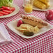 A Bambu disposable bamboo tray with a hot dog, chips, and a red apple.