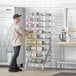 A man standing next to a Regency aluminum can rack full of cans.