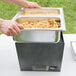 A person holding a Sterno Silver Vein chafing dish with trays of food.