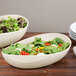 Two Osslo oval melamine bowls of salad on a table.