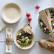 A Bambu Veneerware shallow bamboo bowl with salad and bread on a table.